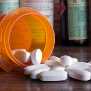 White prescription opioids spilling out of orange container.