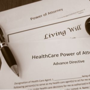 ACP papers reading "Living Will" and "HealthCare Power of Attorney" with a pen laid on top of them.