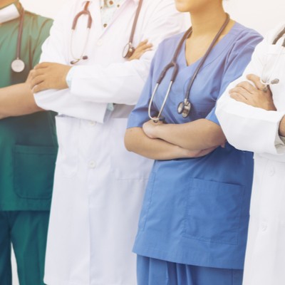 A primary care team in scrubs or white coats, arms folded.