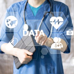 A physician in blue scrubs points at a screen with tiles showing health symbols, a representation of a health learning system.