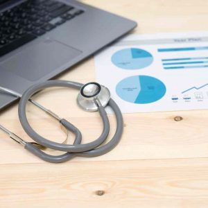 Hospital Finances in a graph, beside a laptop and stethoscope