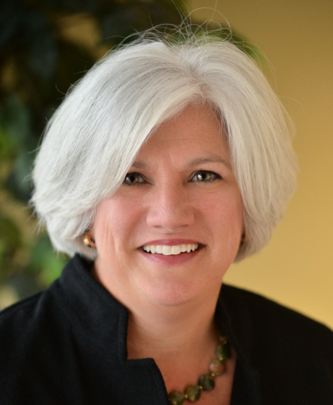 Nancy Baum in a black jacket, smiling