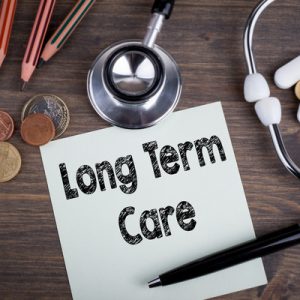 A sign reading "Long term care", surrounded by stethoscope and pencils, indicating long-term support and services.