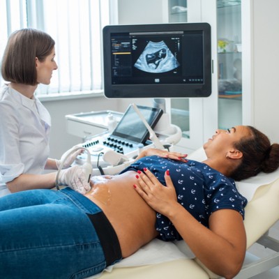 Woman having ultrasound done on belly by female health care worker