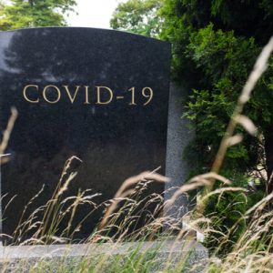 Headstone with "COVID-19" written on it, representing the need for interventions