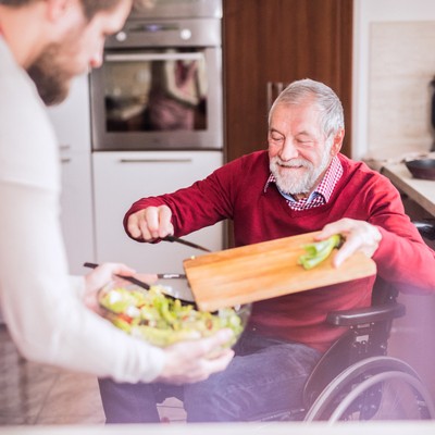 Older gentleman in a wheelchair chopping vegetables for dinner
