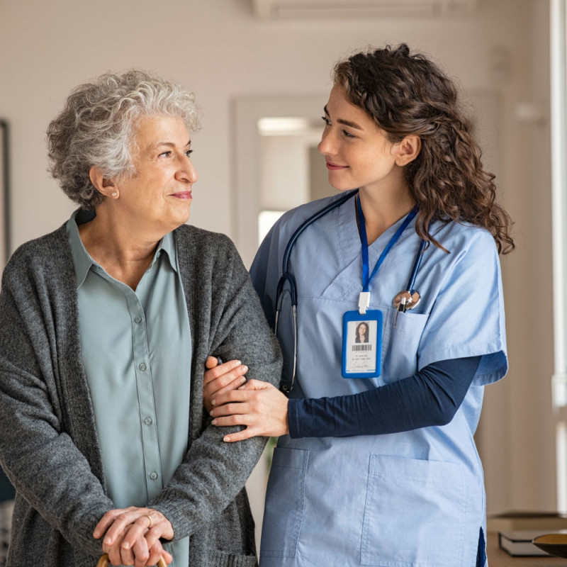 Female caregiver and elderly woman smiling at one another