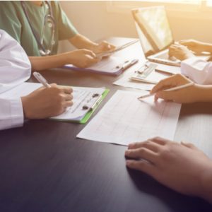 Four healthcare professionals sit at a table looking over paperwork.