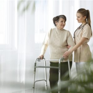 A nurse helps a person using a walker.