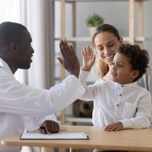 A behavioral health consultant high-fives a child.