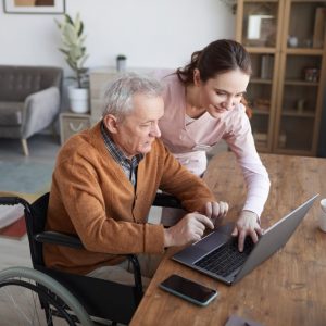 A man in a wheelchair accesses telehealth on laptop