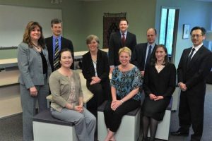 A photo of 9 health policy fellows in business dress sitting and standing together.