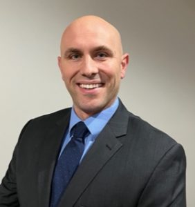 Photo of Jason Fair, smiling in a suit and tie