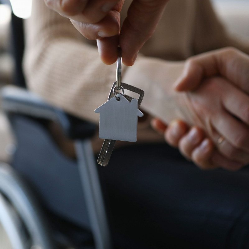 Person in wheelchair shakes hands with someone holding a house key