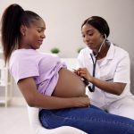 Ob/Gyn examines expecting mom during prenatal visit to prevent maternal mortality