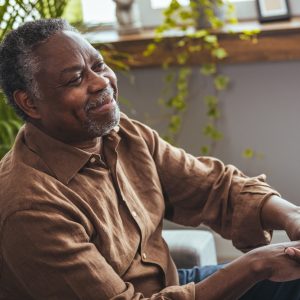 A Black man holds the hands of a direct care worker.