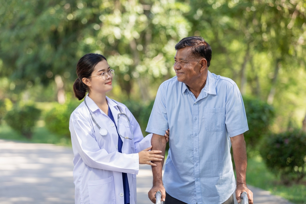 Doctor helps elderly man walk with a walker