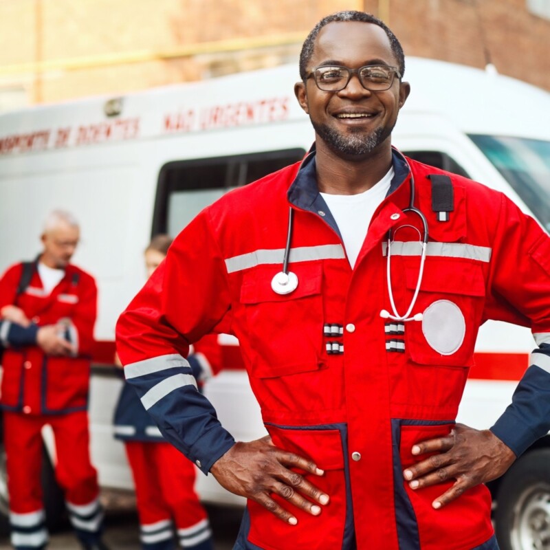 A community paramedic stands smiling, with hands on hips.