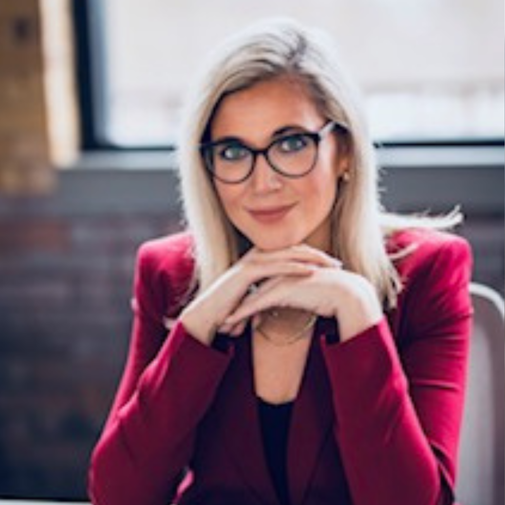 Kelly Ainsworth sits at a desk smiling.