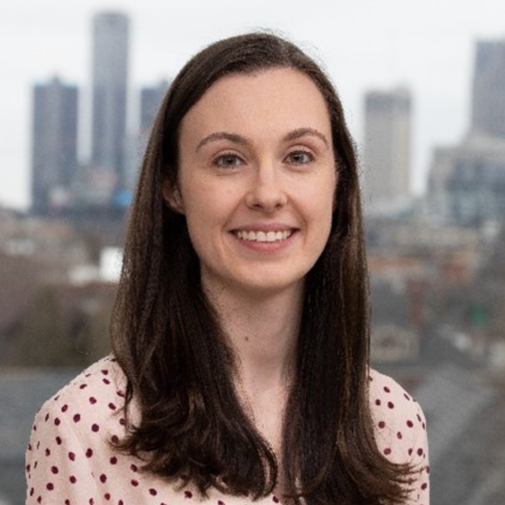 Megan in a pink shirt with a cityscape in the background.