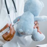 Doctor demonstrates a vaccine on a blue teddy bear