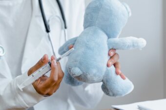 Doctor demonstrates a vaccine on a blue teddy bear